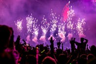 Vibrant EDM concert scene with fireworks, smoke, and enthusiastic crowd enjoying the music.